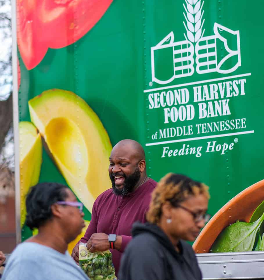 Smiling people in front of a second harvest truck