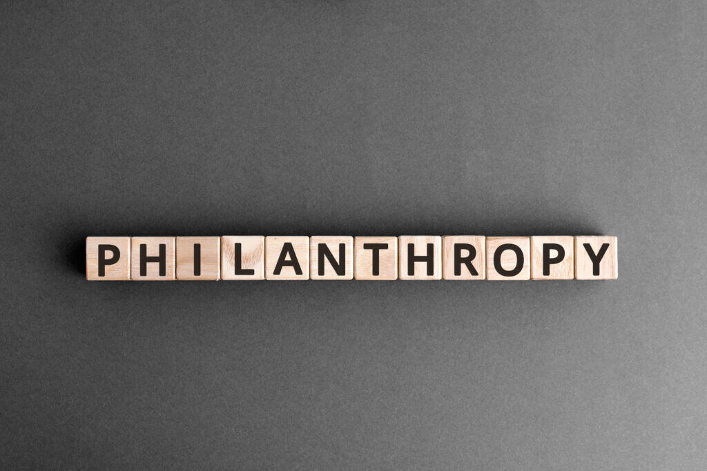 Wooden blocks with black letters spell out the word PHILANTHROPY on a flat, dark gray surface, highlighting the spirit of philanthropy at Second Harvest.