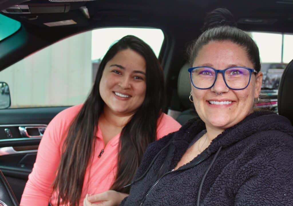 Stephanie and her daughter smile from their car after receiving healthy food to support eating healthy on a budget for blood pressure control at a Second Harvest food distribution.