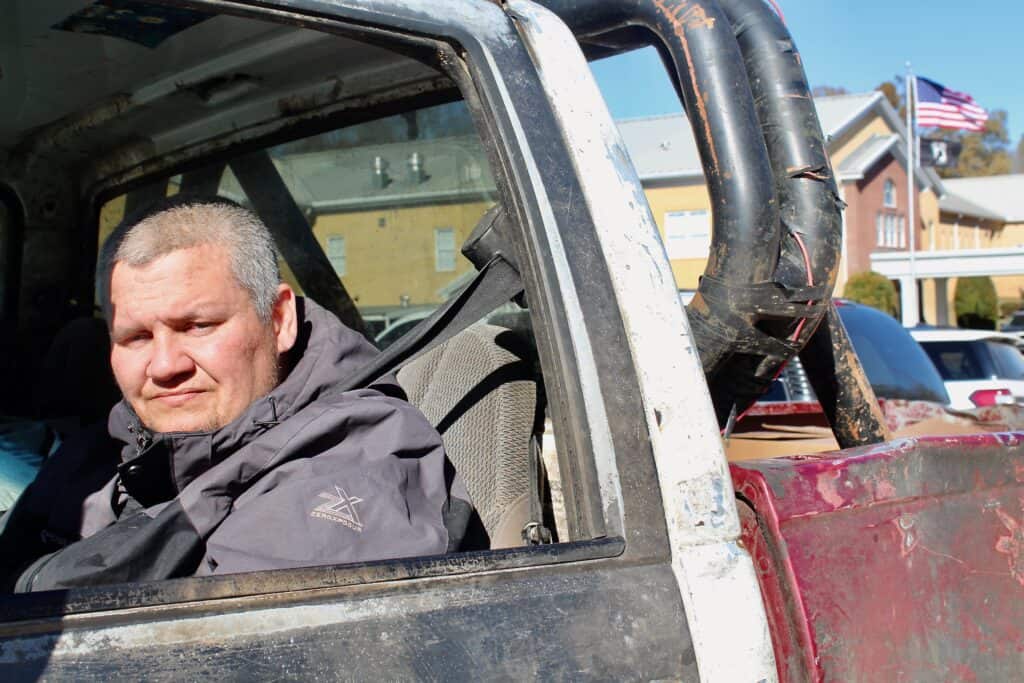 Chris, who faces PTSD and agoraphobia, sits in his truck outside a food distribution, showing the emotional toll of hunger and how Second Harvest helps him cope.
