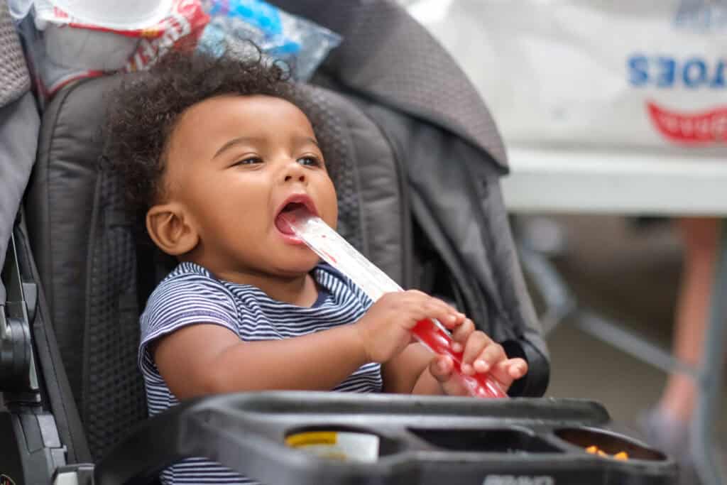 Brooke’s young grandson enjoys a red popsicle while sitting in a stroller at a Second Harvest Summer Food Programs for Kids.