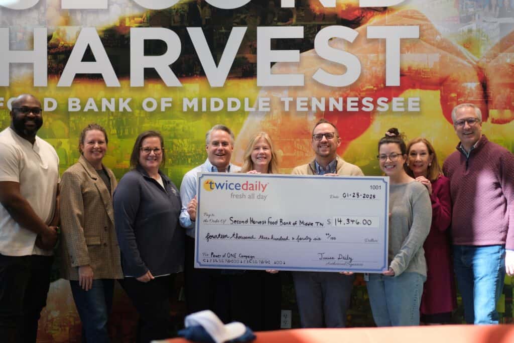 Twice Daily Fuels Tennessee with the Power of ONE. Nine people stand smiling in front of a colorful Second Harvest wall, holding a large ceremonial check for $14,376 made out to the Second Harvest Food Bank of Middle Tennessee from Twice Daily.