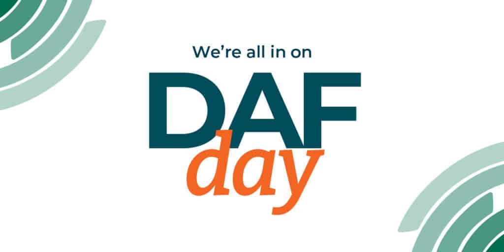 Text graphic with the words Were all in on DAF day in teal and orange letters, with abstract green circular designs in the top left and bottom right corners on a white background.