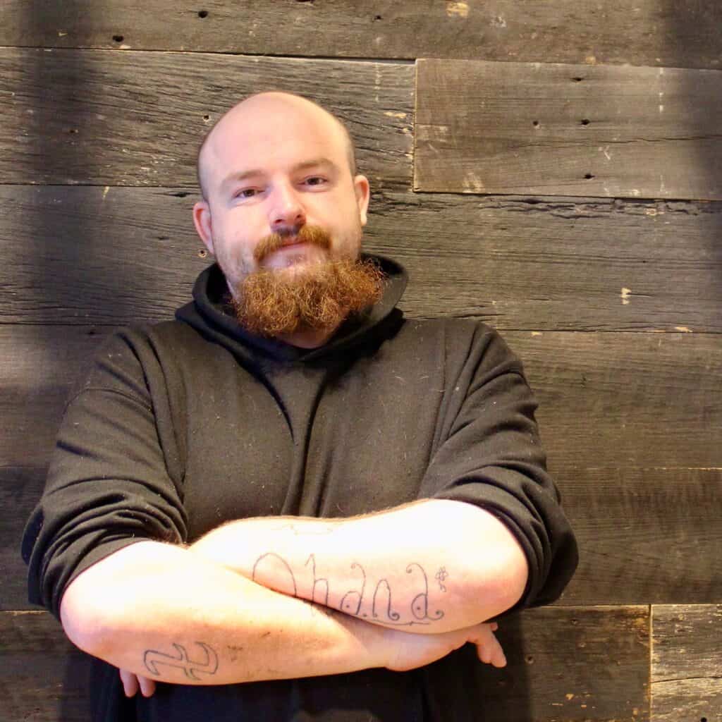 Tyler stands with his arms crossed and a calm expression, showing confidence and resilience. His story illustrates how food affects mental health, helping manage stress and stability while living with schizophrenia.