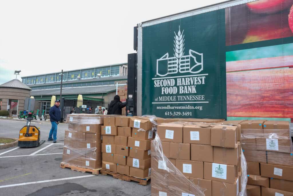 A truck labeled Second Harvest Food Bank of Middle Tennessee is parked beside stacks of cardboard food boxes, as volunteers organize and distribute supplies outdoors—showcasing how Middle Tennessee showed resilience during SNAP cuts and Winter Storm Fern.
