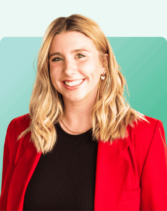 A woman with wavy blonde hair, wearing a bright red blazer over a black top, smiles at the camera. The background is a gradient of mint green to teal with rounded corners.