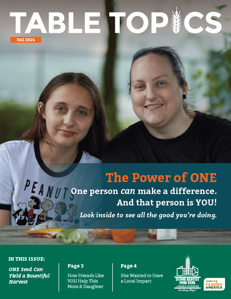 Two women sit close together and smile at the camera; one wears a Snoopy shirt. The magazine title reads TABLE TOPICS and the main headline is The Power of ONE: One person can make a difference..